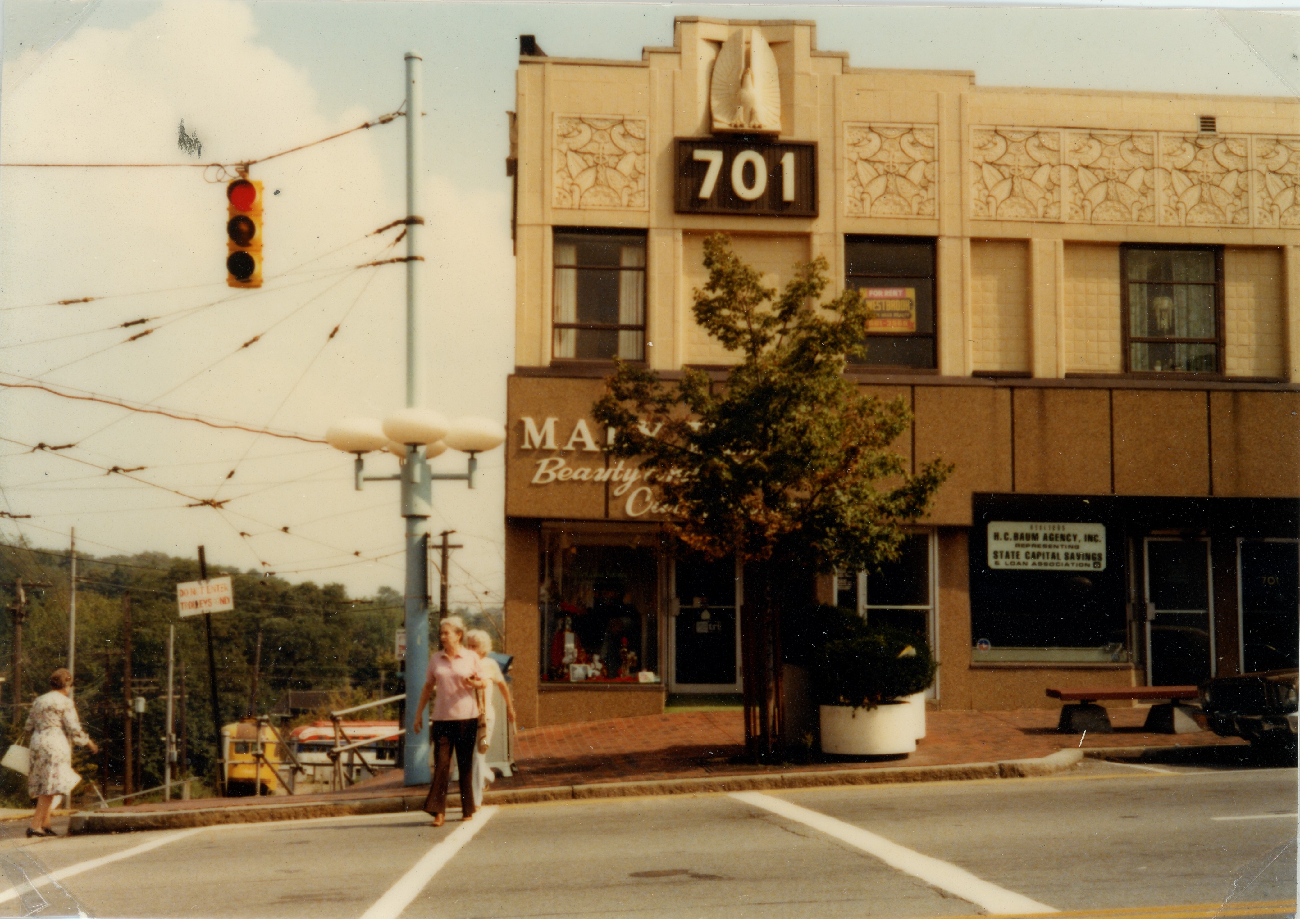Street view of a light tan and reddish brown building with larger numbers on the front reading 701
